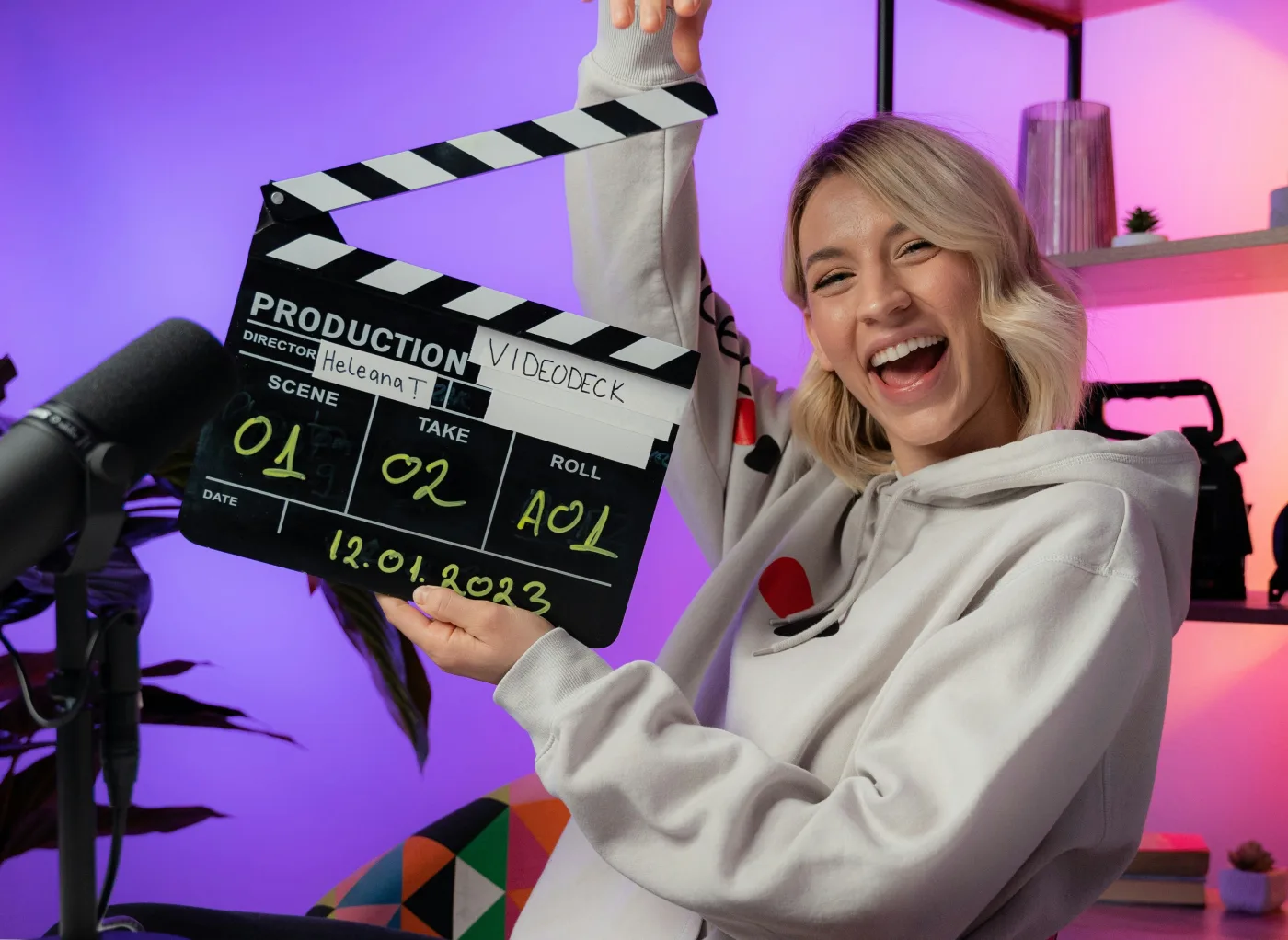 A creator holding a clapperboard in a studio